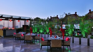 Un espace de restauration en plein air avec des tables et des chaises, un bar et des statues rouges décoratives.