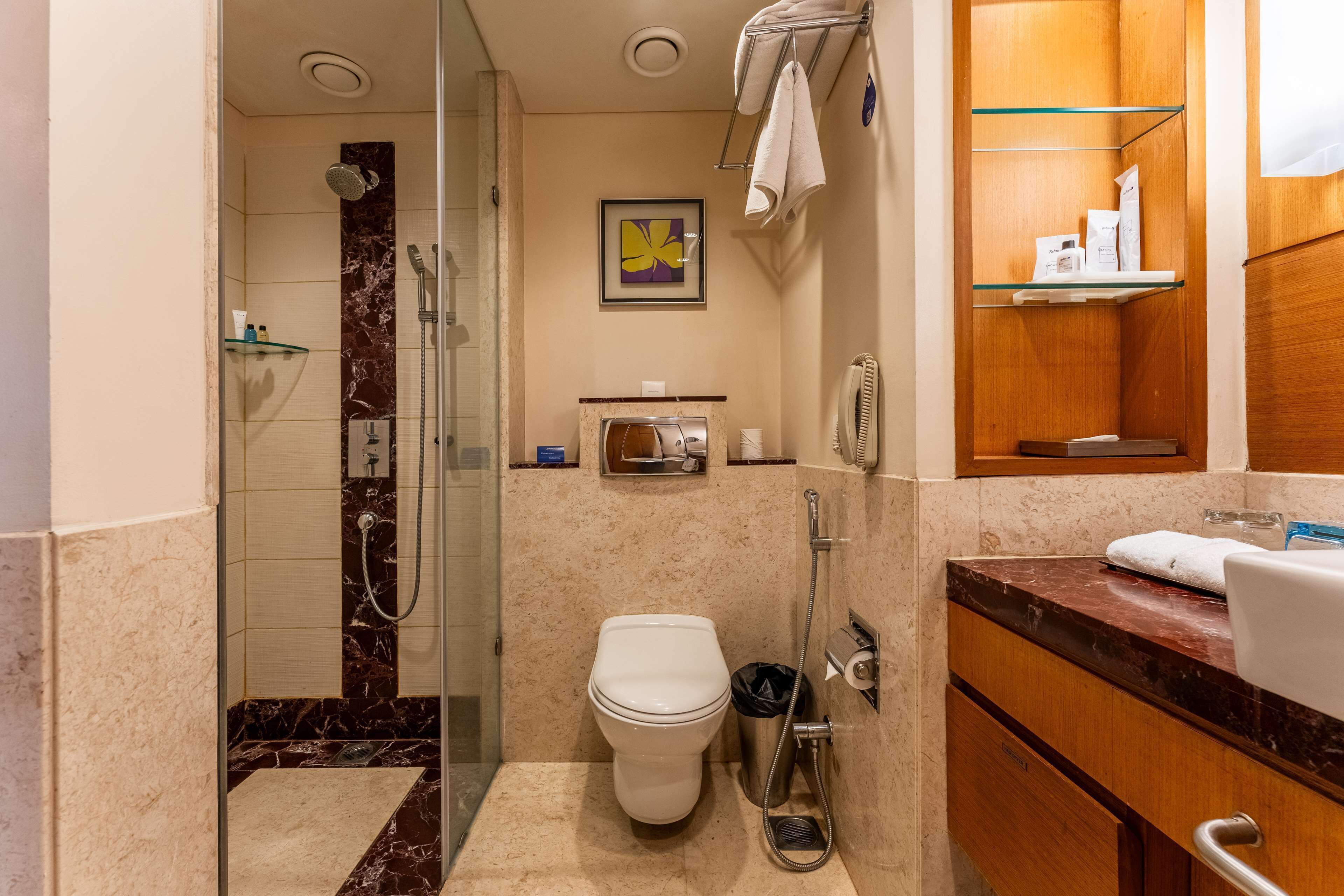Un baño moderno con ducha de vidrio, inodoro blanco y suelo de mármol.