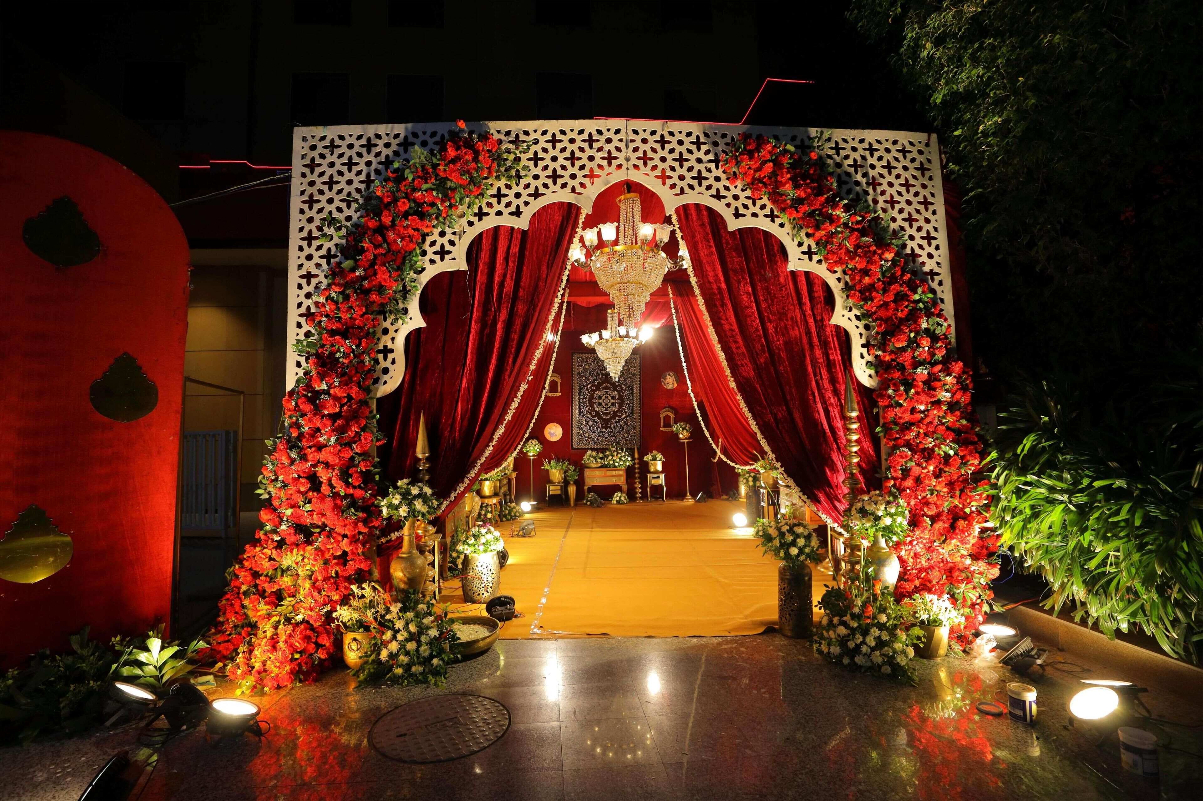 Une entrée somptueuse, ornée de rideaux rouges, d’un lustre et de compositions florales.