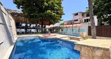 Una piscina al aire libre, sombrillas, sillones reclinables de piscina