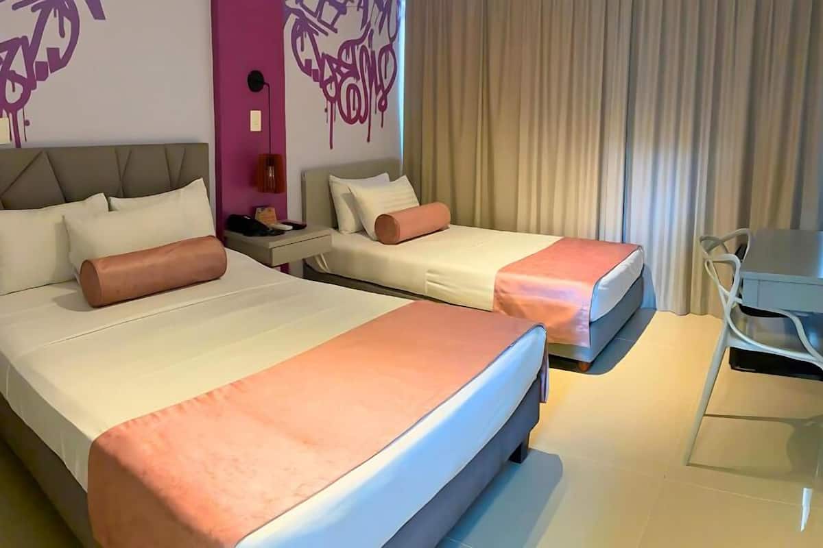 A hotel room with two beds, a desk, and a chair.
