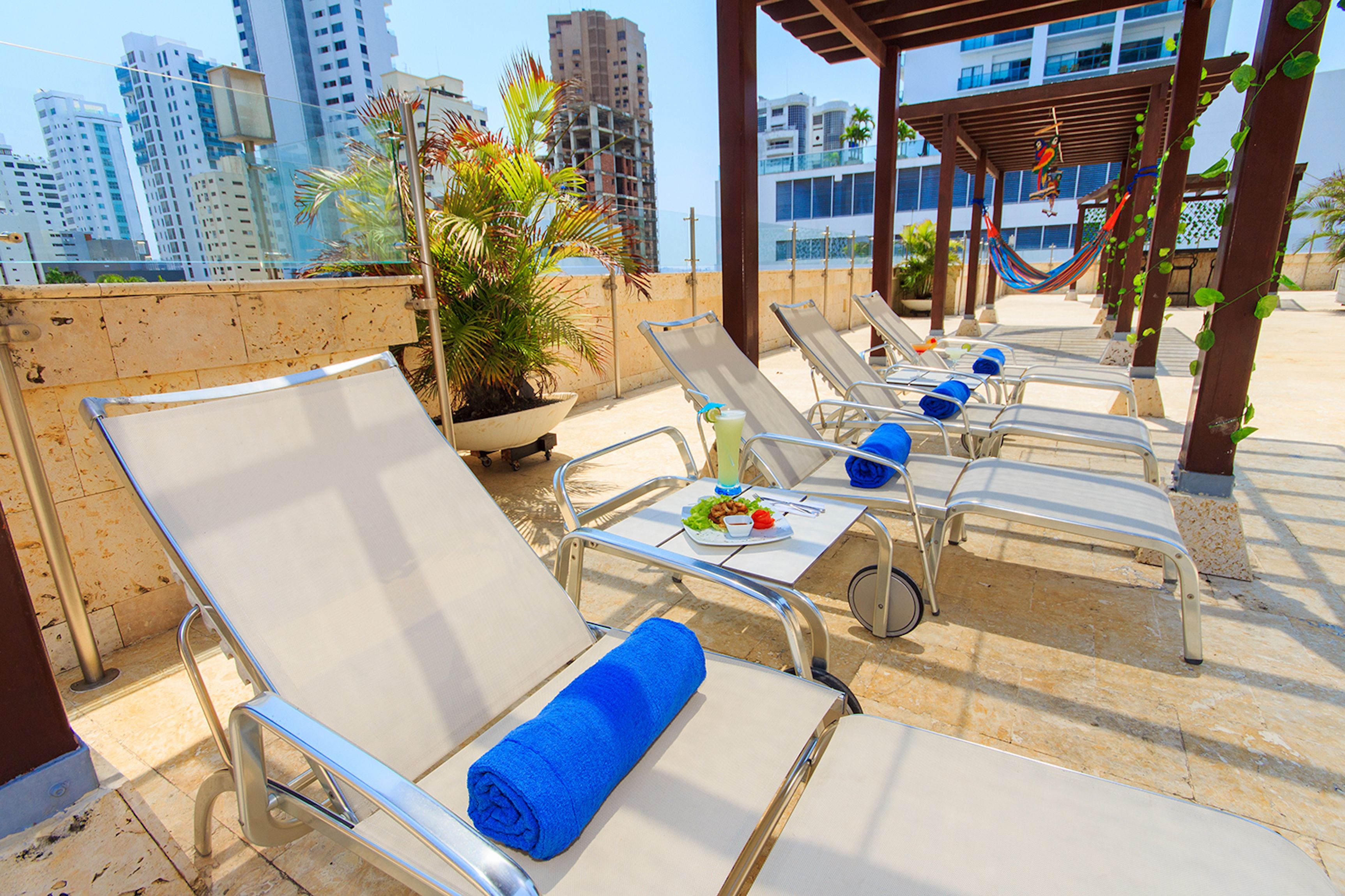 Terraza en la azotea con sillones de sol, una planta en maceta y vista panorámica de la ciudad.