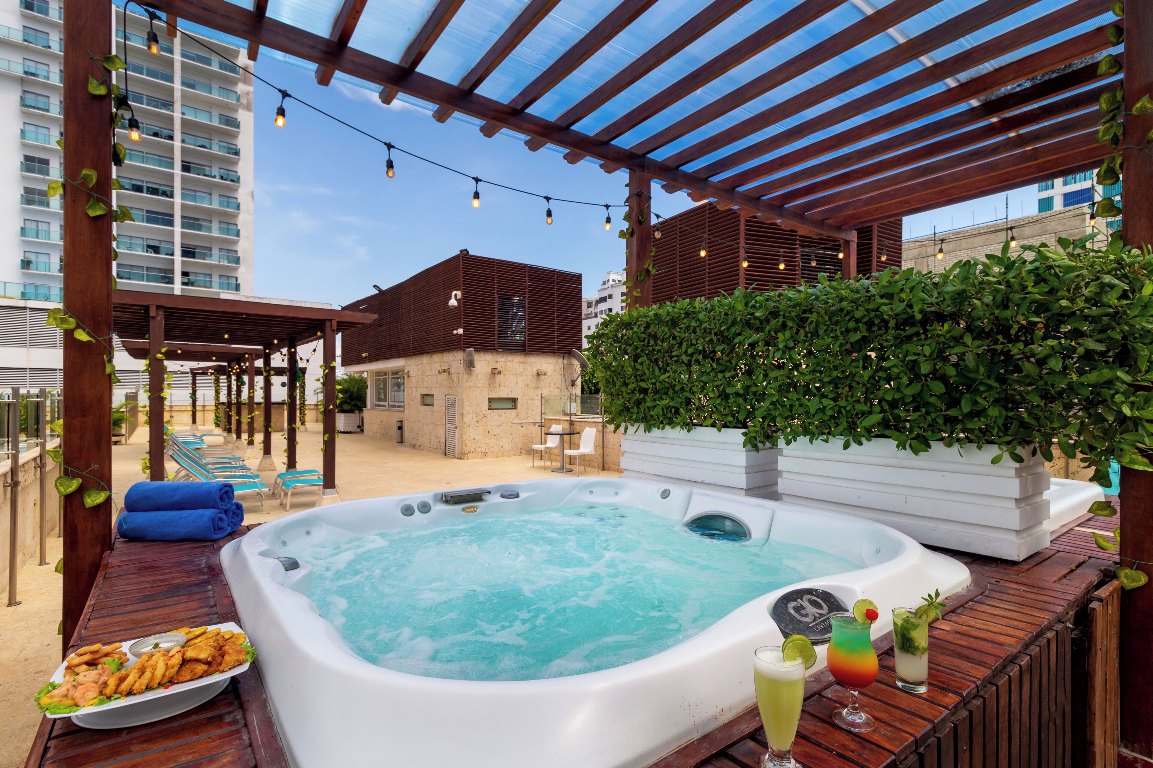 A hot tub with a poolside area, including lounge chairs and a dining table with food.