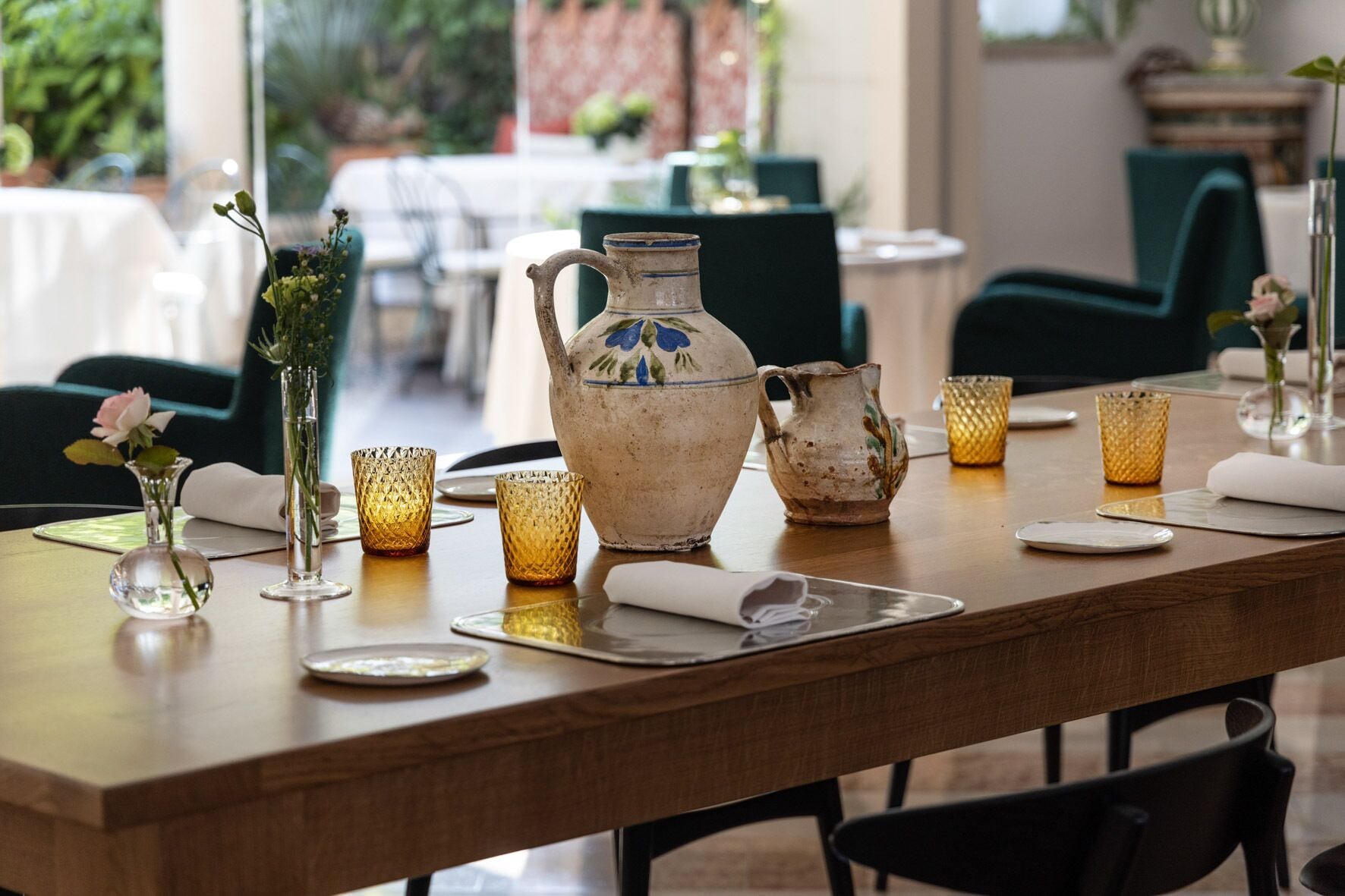 A dining table set with a pitcher, glasses, and a vase with flowers.