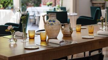 A dining table set with a pitcher, glasses, and a vase with flowers.