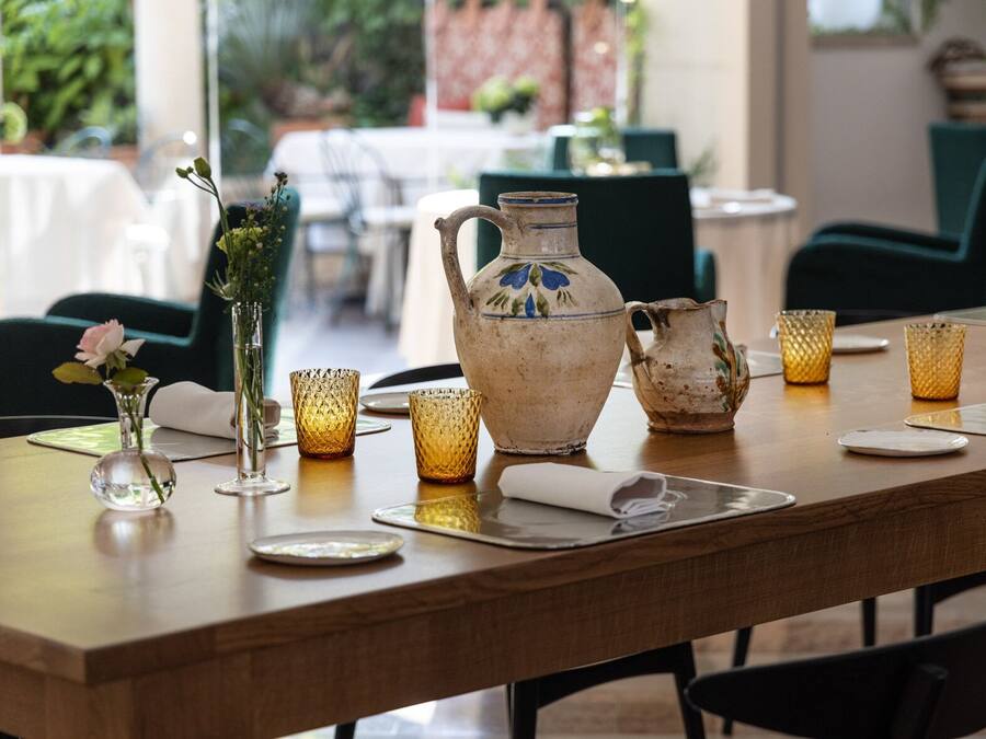 A dining table set with a pitcher, glasses, and a vase with flowers.