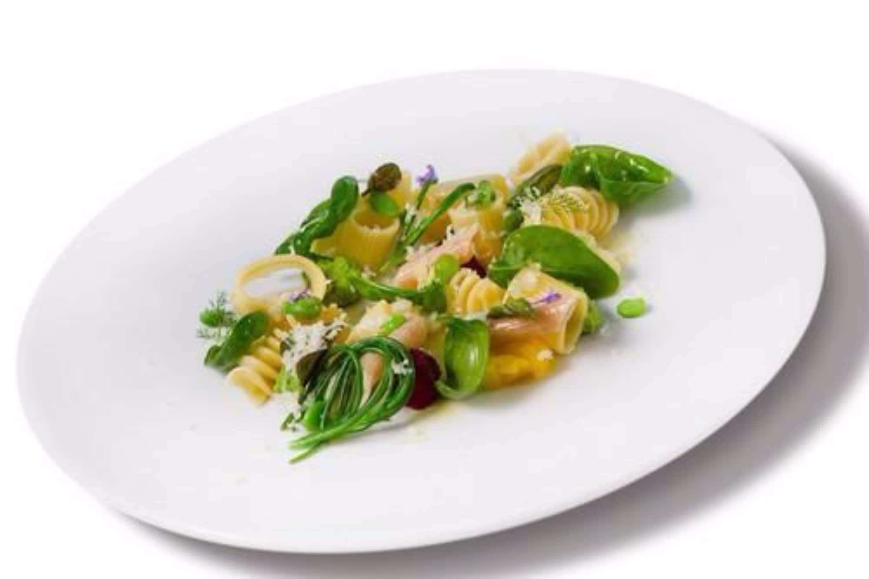 A white plate with pasta, greens, and cheese.
