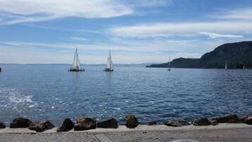 A coastal scene with a rocky shoreline and sailboats on the water.