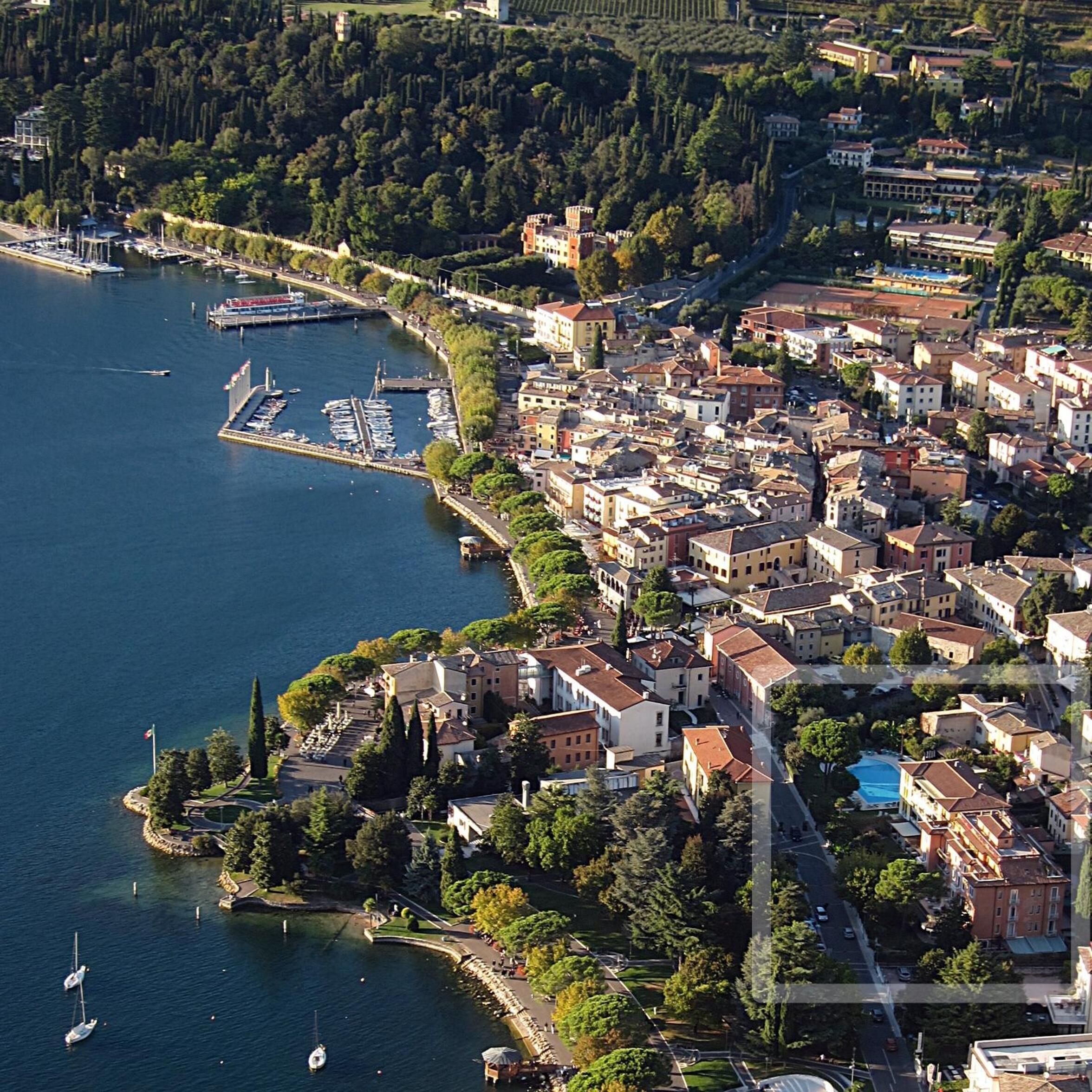 Vue aérienne d’une ville côtière avec un port de plaisance, des immeubles d’habitation denses et un mélange de styles architecturaux.