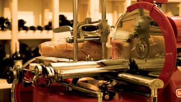 A meat slicer in a kitchen with shelves in the background.
