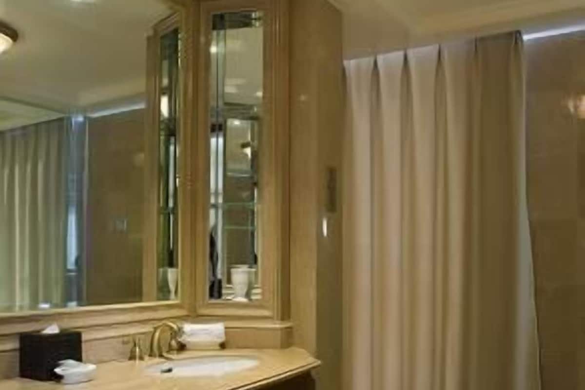 Un baño con un espejo grande, dos lavamanos, un mueble de tocador con cajones y una zona de ducha con cortinas.