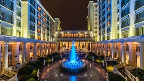 Un hotel elegante con una fuente central, arquitectura simétrica y una entrada formal.