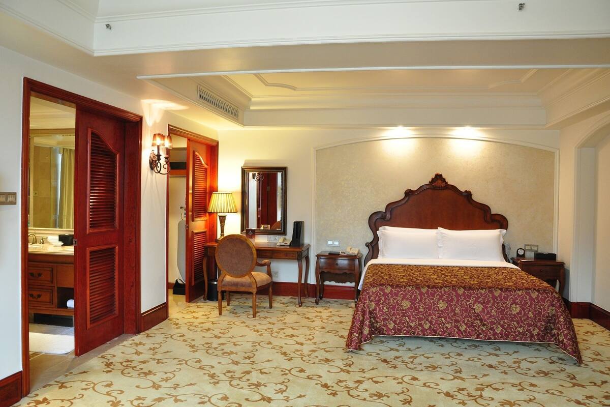 Habitación de hotel con una cama grande, un escritorio, una silla y un espejo.