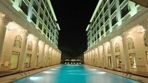 Una piscina con un edificio simétrico a cada lado, con arcos en puertas y ventanas.
