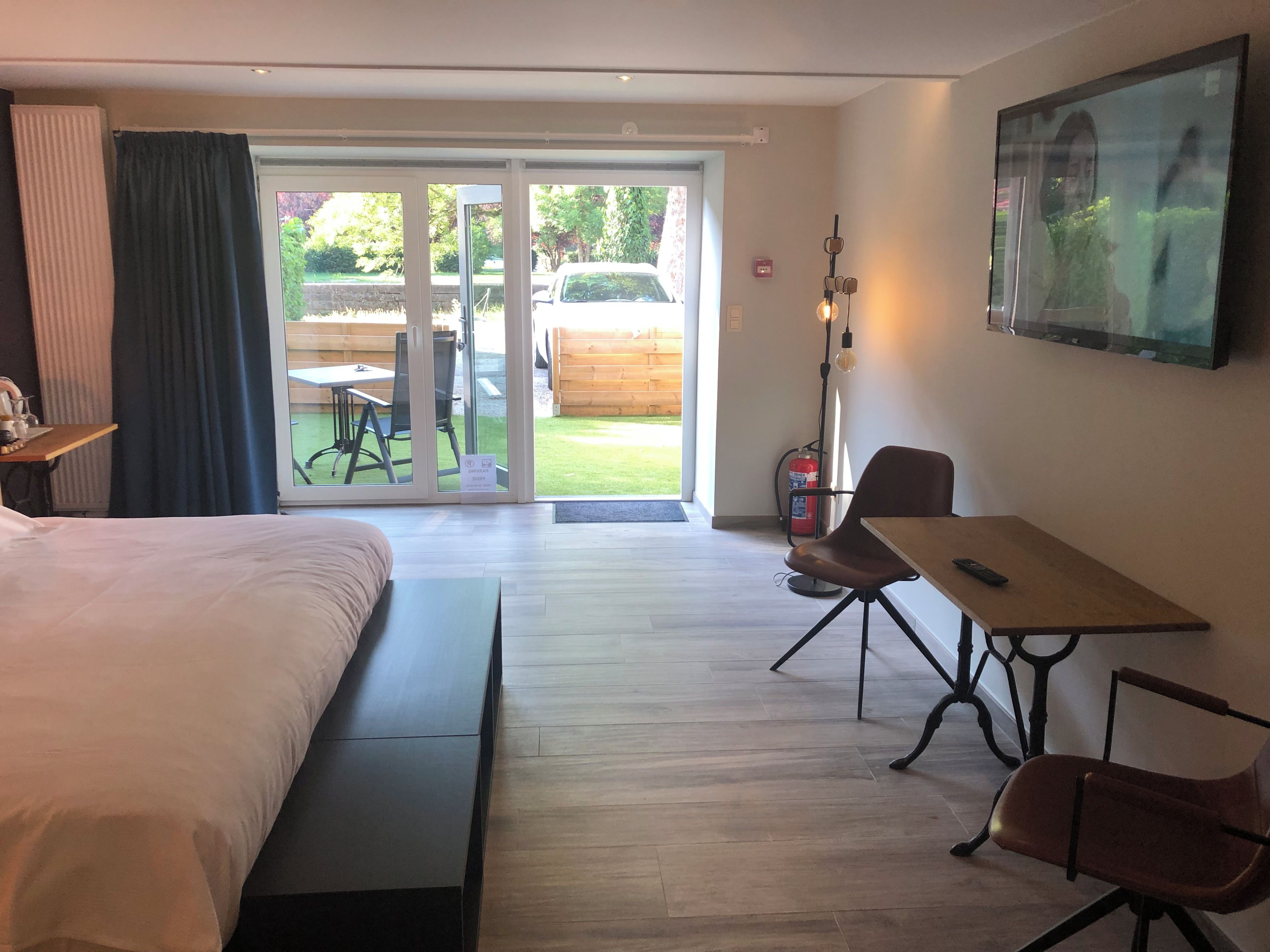 Une chambre d’hôtel équipée d’un lit, d’une table, d’une chaise, d’un extincteur et offrant une vue sur l’extérieur.