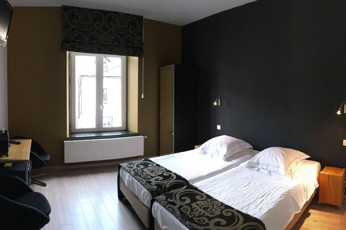 Un dormitorio con cama, escritorio, silla, ventana y radiador.