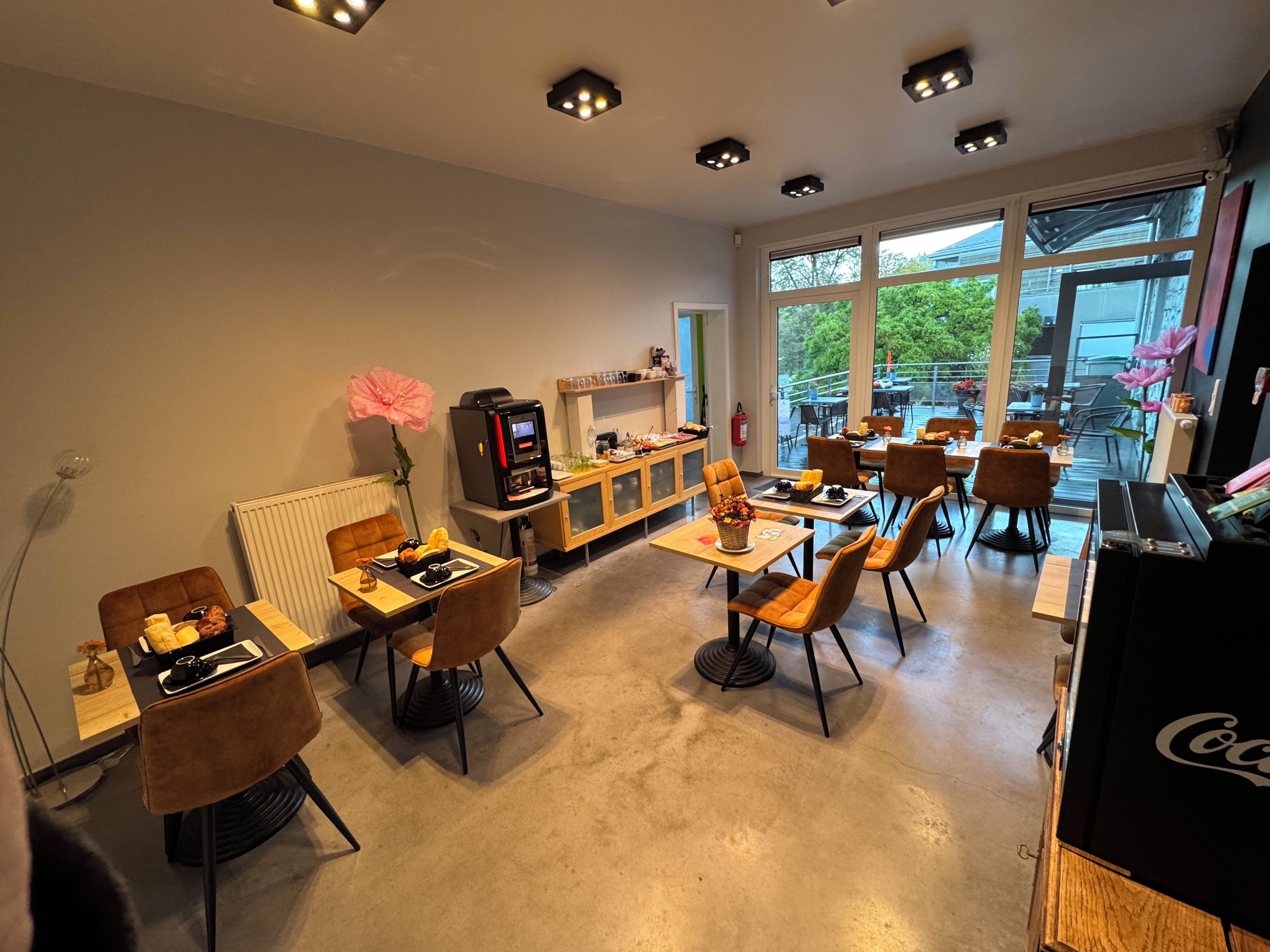 A dining area with tables and chairs, a coffee machine, and a piano.
