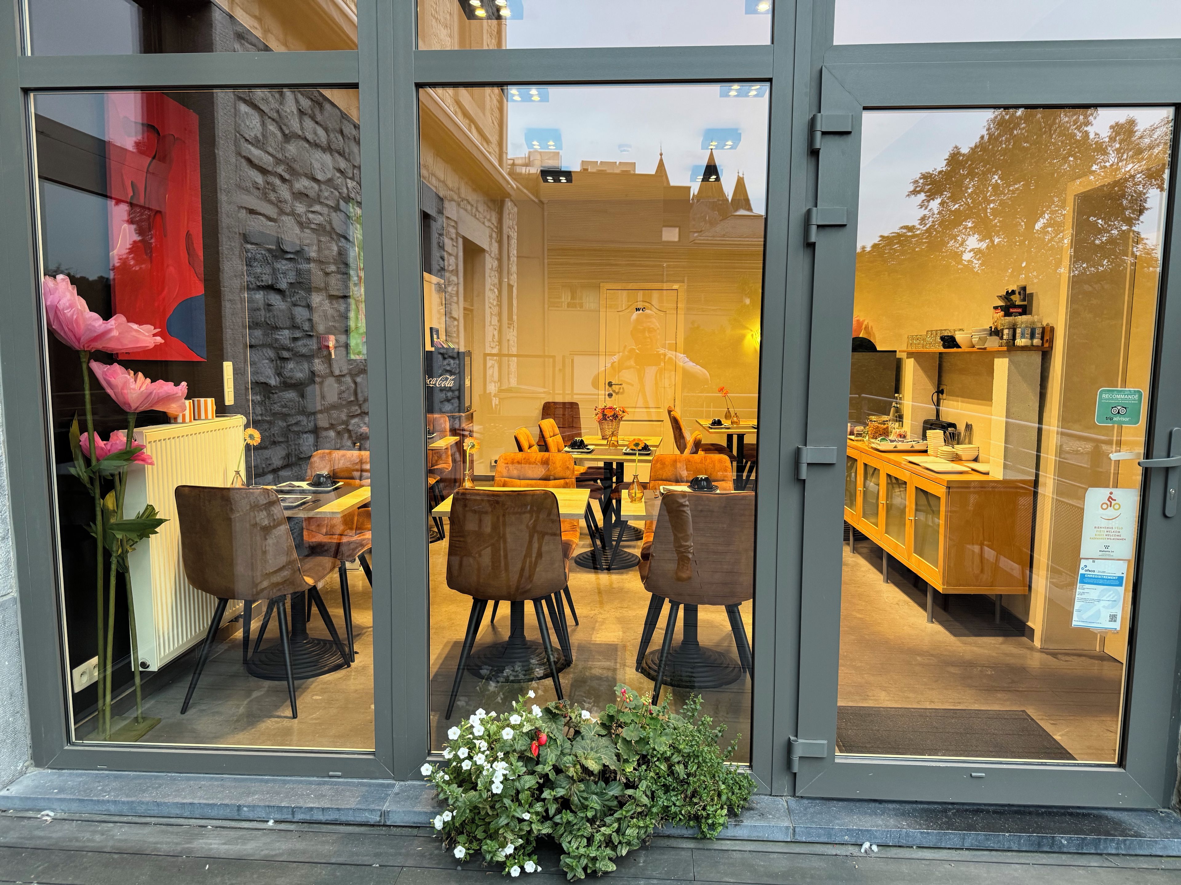 Un restaurant doté d’une façade en pierre, d’une salle à manger intérieure et offrant une vue sur le paysage urbain grâce à de grandes fenêtres.