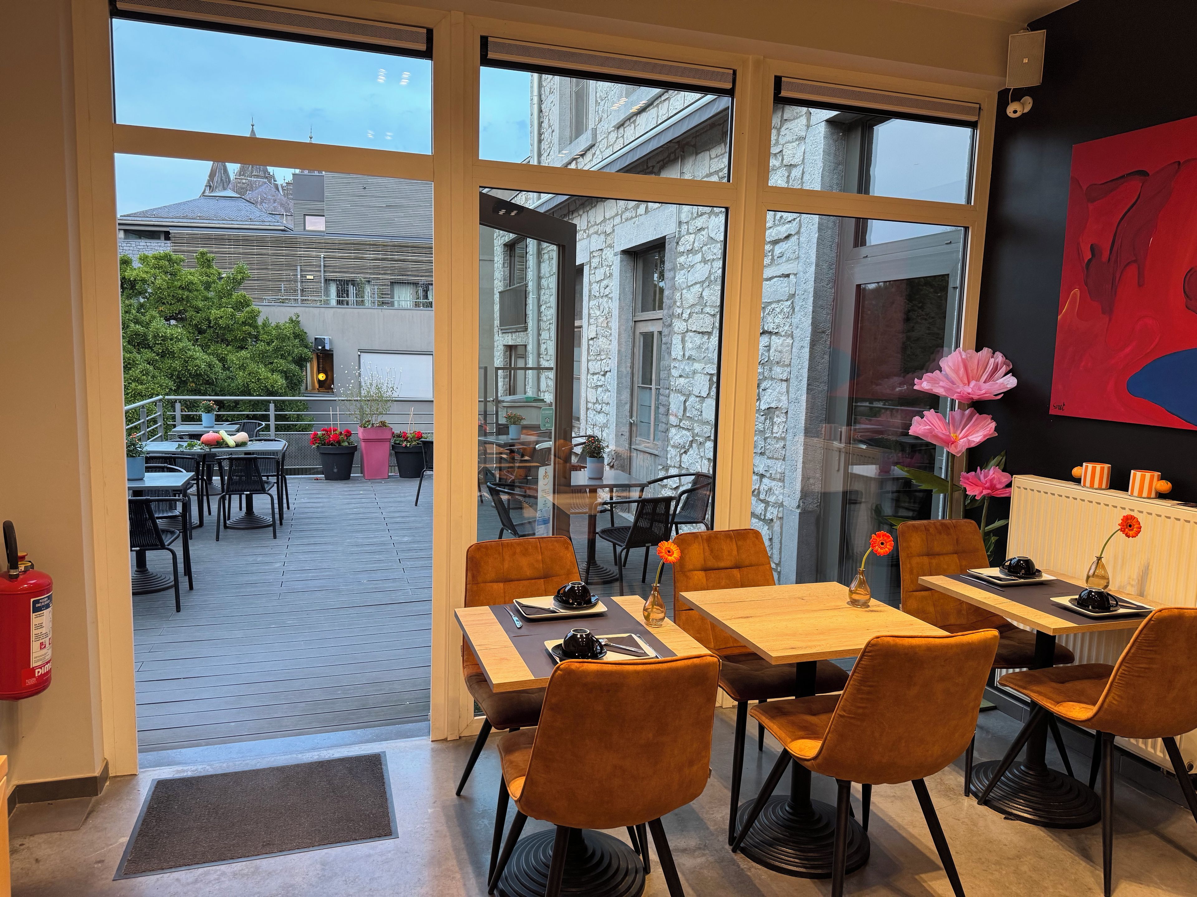 Un espace de restauration intérieur avec des tables et des chaises, de grandes fenêtres et une vue sur la rue.