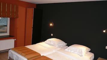 Een hotelkamer met een bed, een raam met zonwering en een wandlamp.