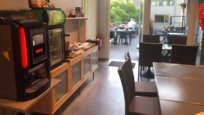 Un espace réservé au petit-déjeuner, équipé d’une machine à café, d’un réfrigérateur et d’une table de buffet.