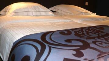 Una cama bien tendida con sábanas blancas y una colcha estampada.