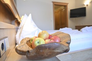 Un bol en bois rempli de pommes, posé sur une table de chevet dans une chambre d’hôtel.