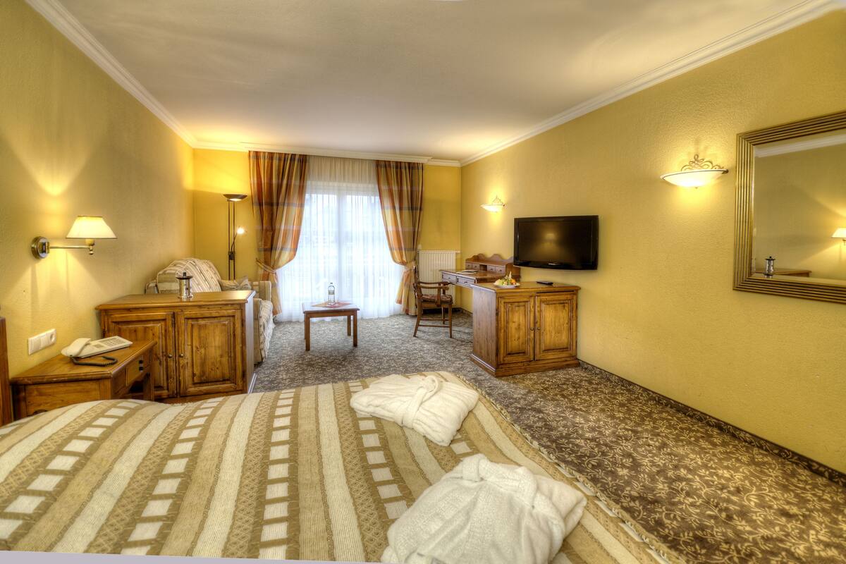A hotel room with two beds, a desk, a chair, a television, and a large mirror.