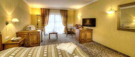 Habitación de hotel con dos camas, un escritorio, una silla, un televisor y un espejo grande.