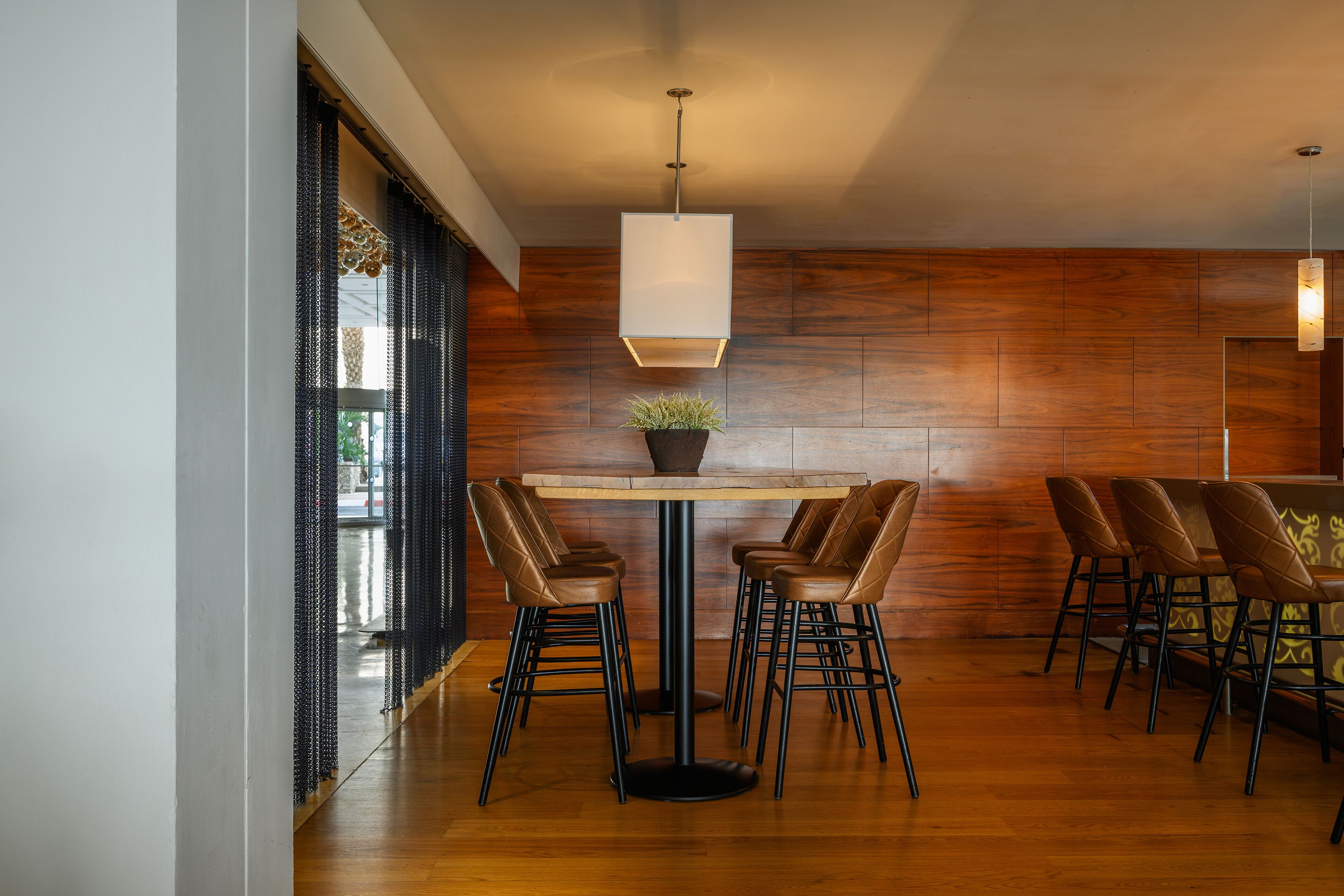 Un comedor moderno con una mesa redonda, seis sillas y una lámpara colgante.