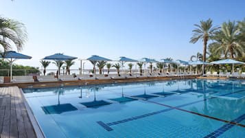 Una piscina techada, una piscina al aire libre, sombrillas