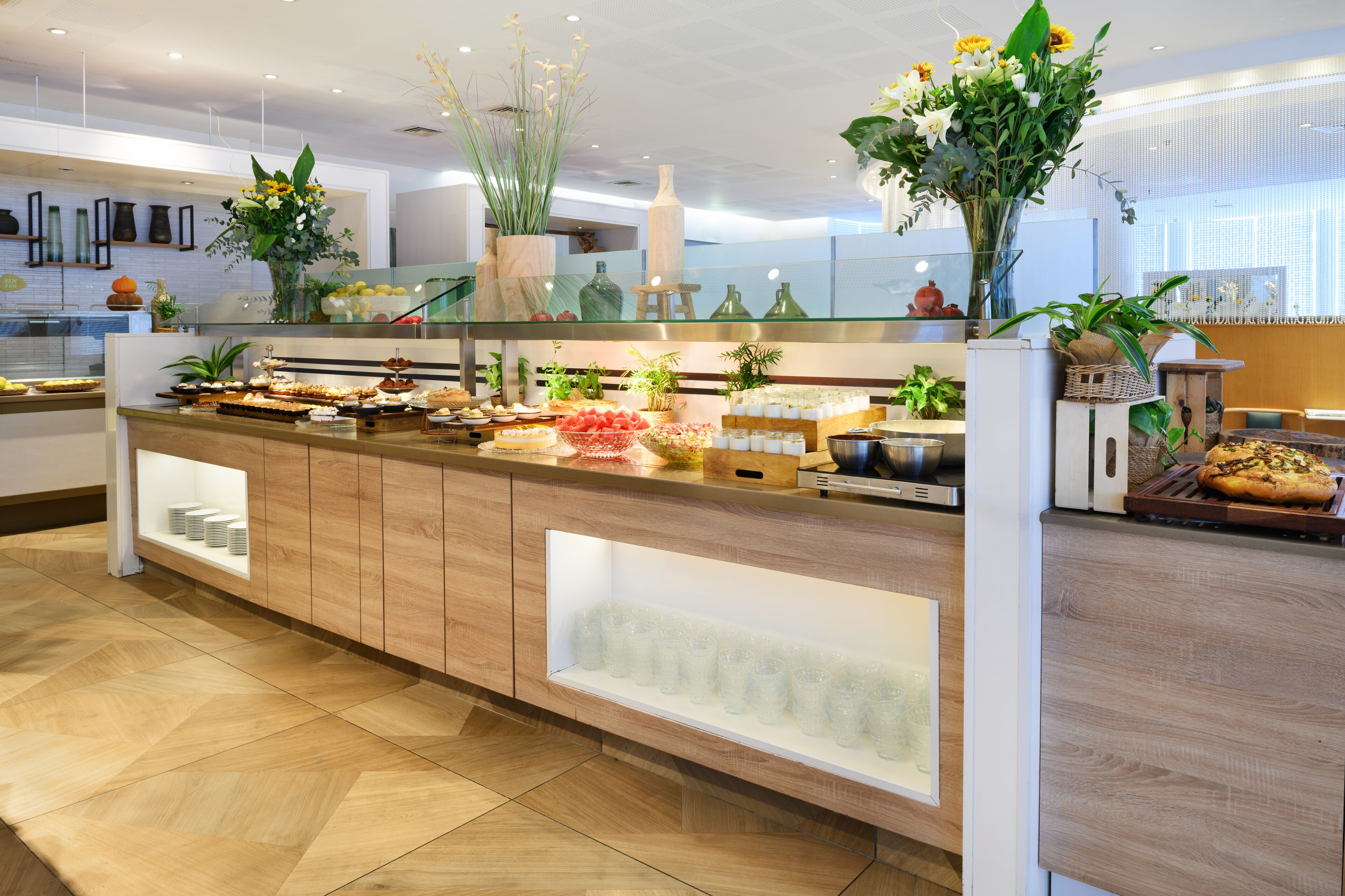 A buffet area with various food items, glassware, and decorative plants.