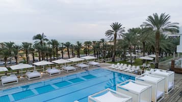 A pool area with lounge chairs and umbrellas, surrounded by palm trees.