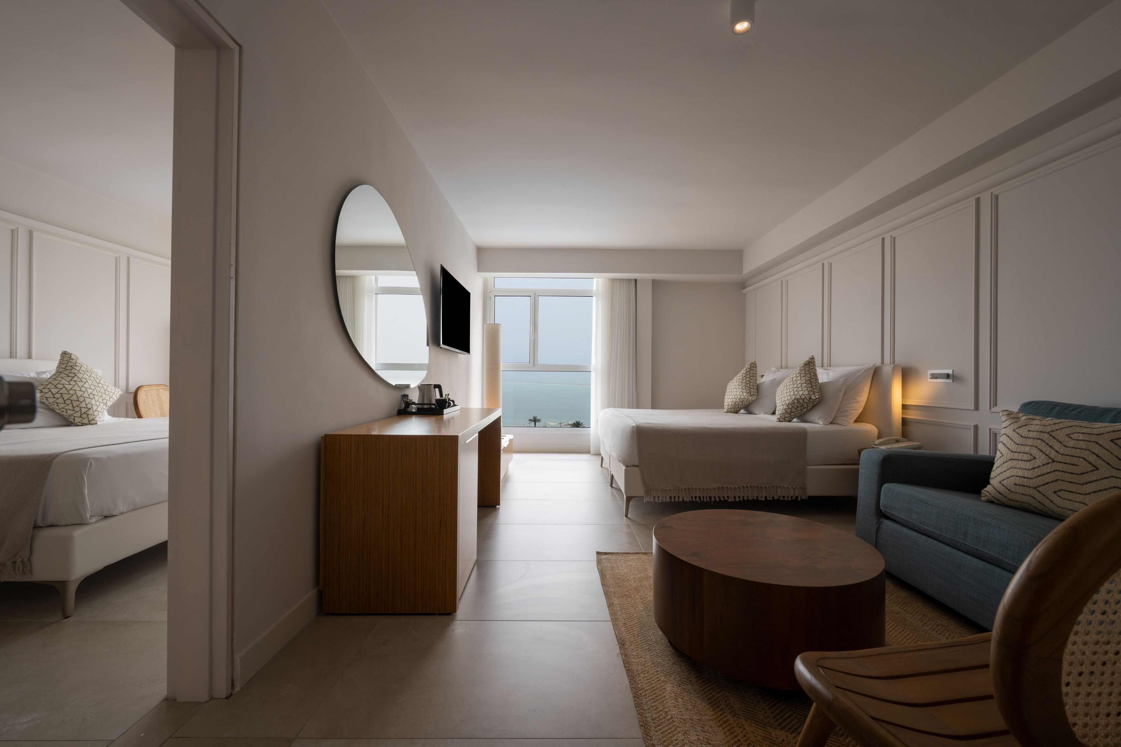A modern hotel room with a bed, a sofa, a coffee table, and a desk.