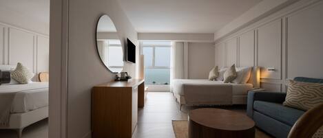 A modern hotel room with a bed, a sofa, a coffee table, and a desk.