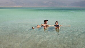Two people floating in clear turquoise water with a mountainous landscape in the background. - Noga By Isrotel Collection (Tamar)