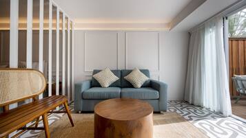 Een moderne woonkamer met een blauwe bank, twee gestreepte kussens, een houten salontafel en een rieten stoel.