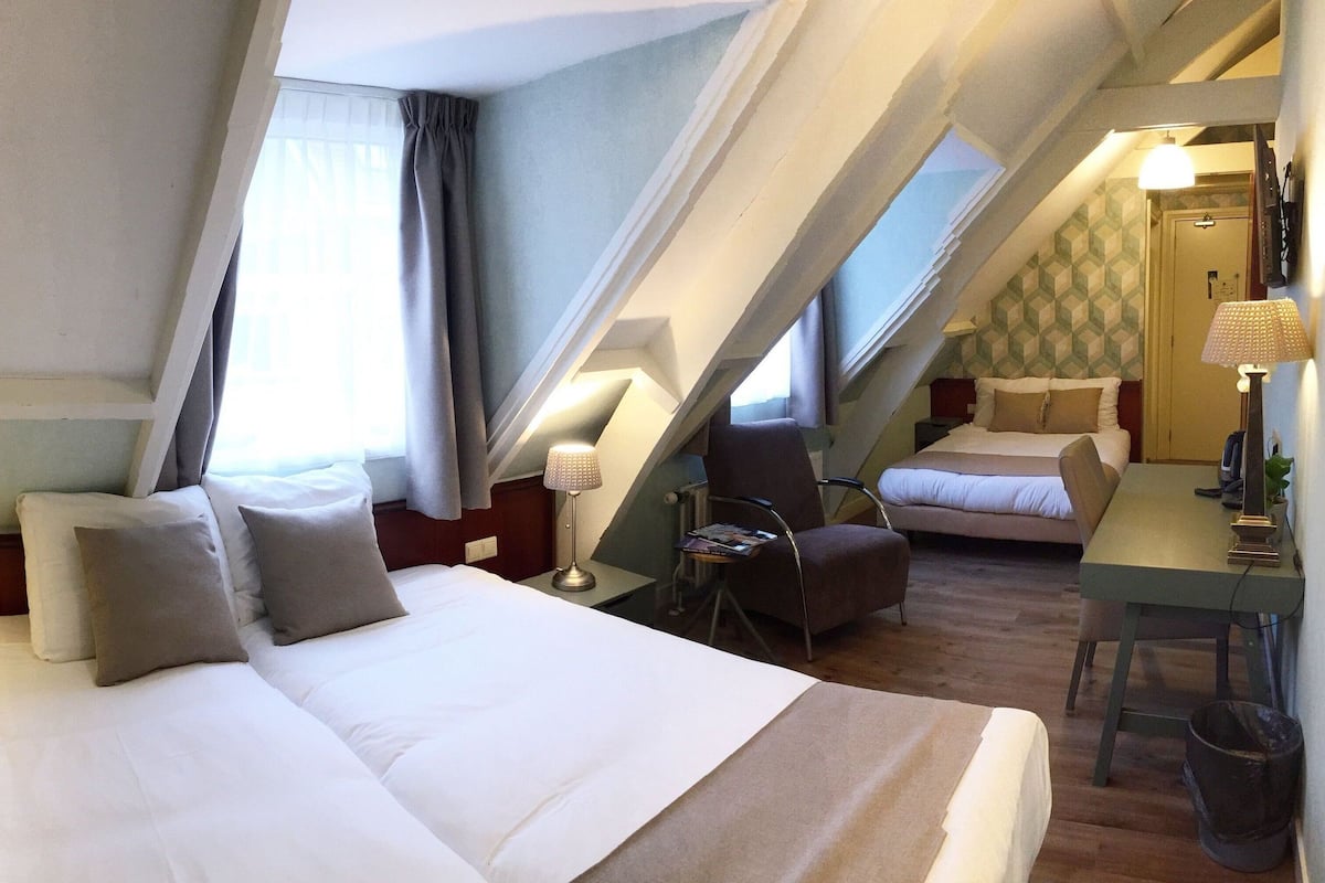 Una habitación de hotel con una cama grande, un escritorio, una silla y una mesita.