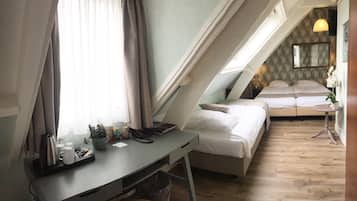 Een slaapkamer met een bureau, twee bedden, een klein tafeltje en een raam met gordijnen.