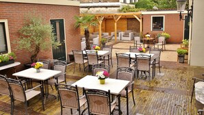 An outdoor patio area with multiple tables and chairs, some with flowers.