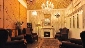 A cozy living room with a fireplace, plush armchairs, and a chandelier.