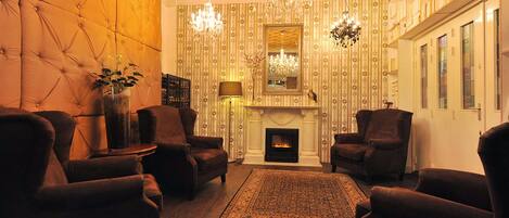 Una sala de estar acogedora con chimenea, sillones cómodos y un candelabro.
