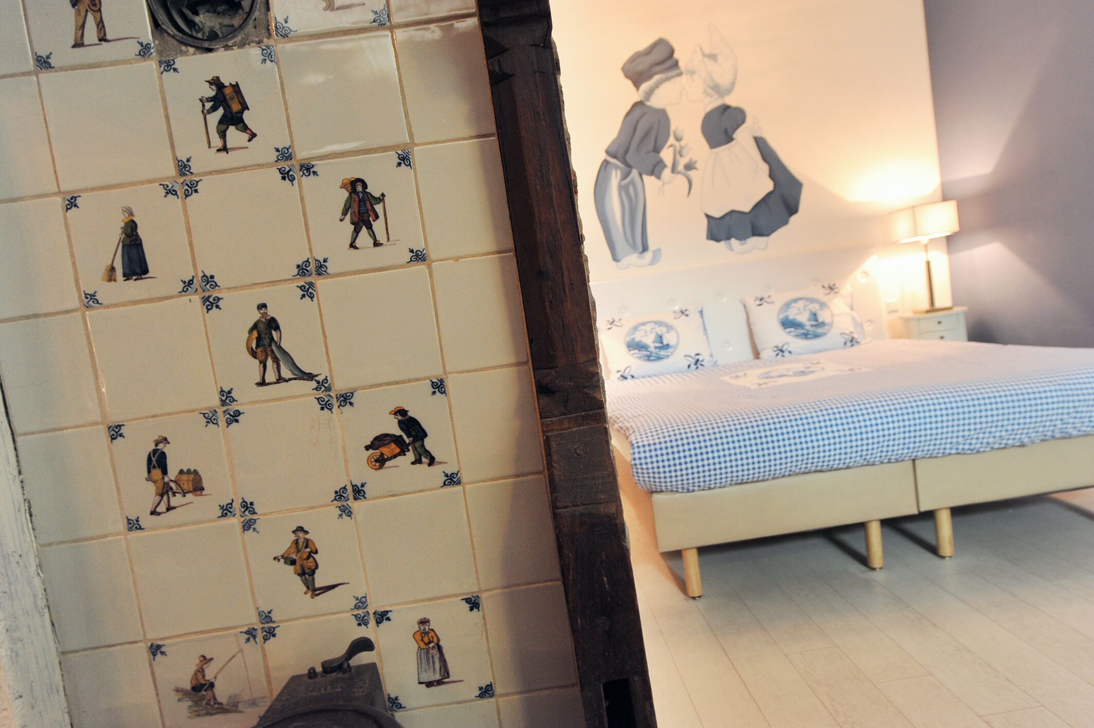 A bedroom with a bed, a nightstand, and a wall with historical tiles.