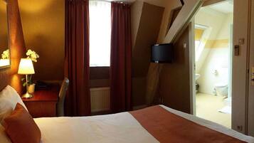 Hotelkamer met een bed, een bureau met lamp, een stoel en uitzicht op de badkamer.