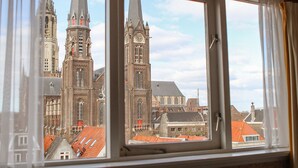 A view of a historic church with two tall spires and a clock tower through a window.