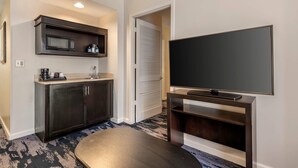 A modern hotel room with a kitchenette, a flat-screen TV, and a patterned carpet. - The Connally Hotel Downtown Atlanta, an Ascend Collection Hotel (Atlanta)