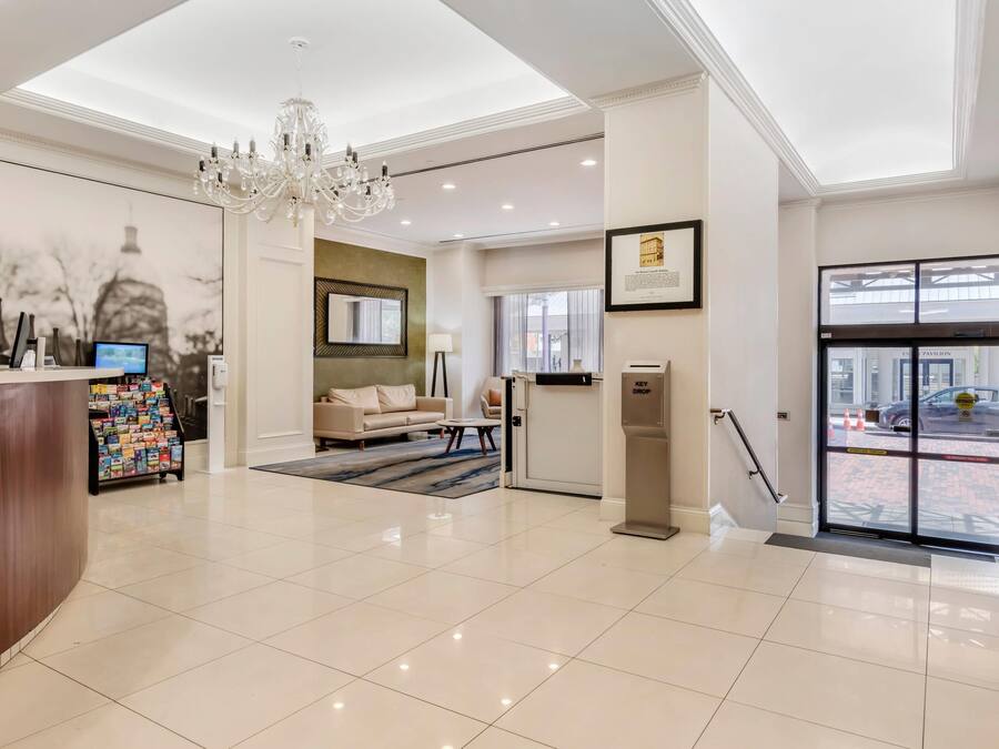 A hotel lobby with a reception desk, a chandelier, a sofa, and a coffee table.