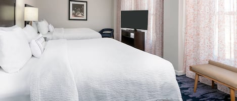 Una camera d'albergo con un letto grande, una televisione, una scrivania e una panca.