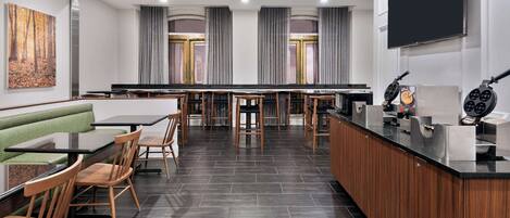 A modern restaurant with a long counter, wooden chairs, and a green booth.