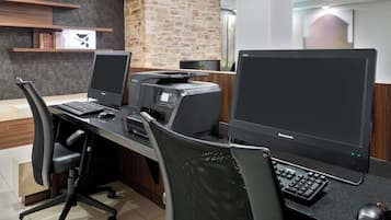 A modern office space with two desktop computers, a printer, and a keyboard on a desk.